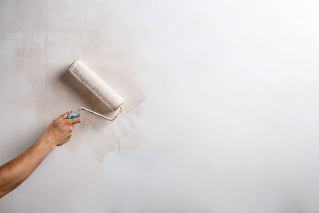 Close up of hand painting wall with roller