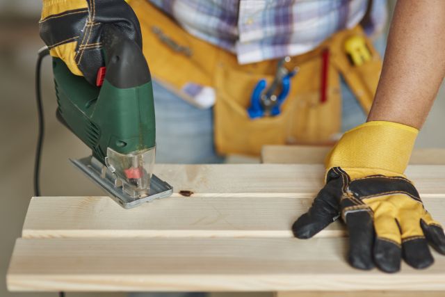 Close up on experienced carpenter drilling in wooden plank